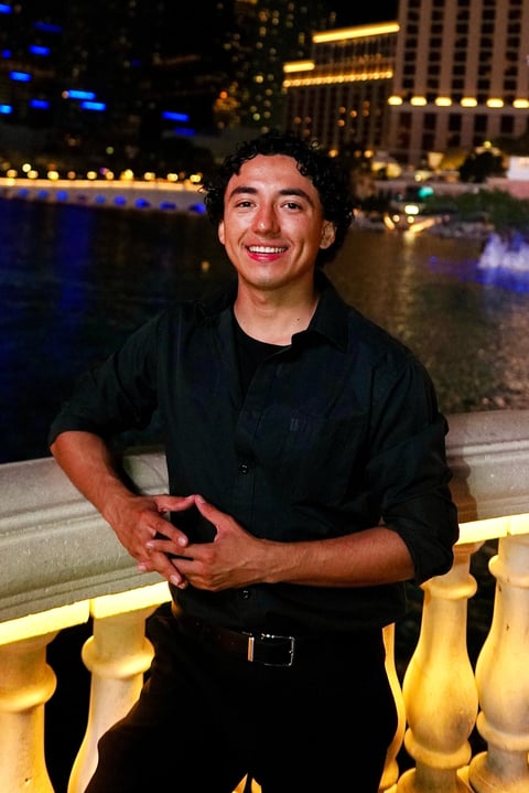 Romero Brothers - Man in black shirt smiling at night with illuminated cityscape